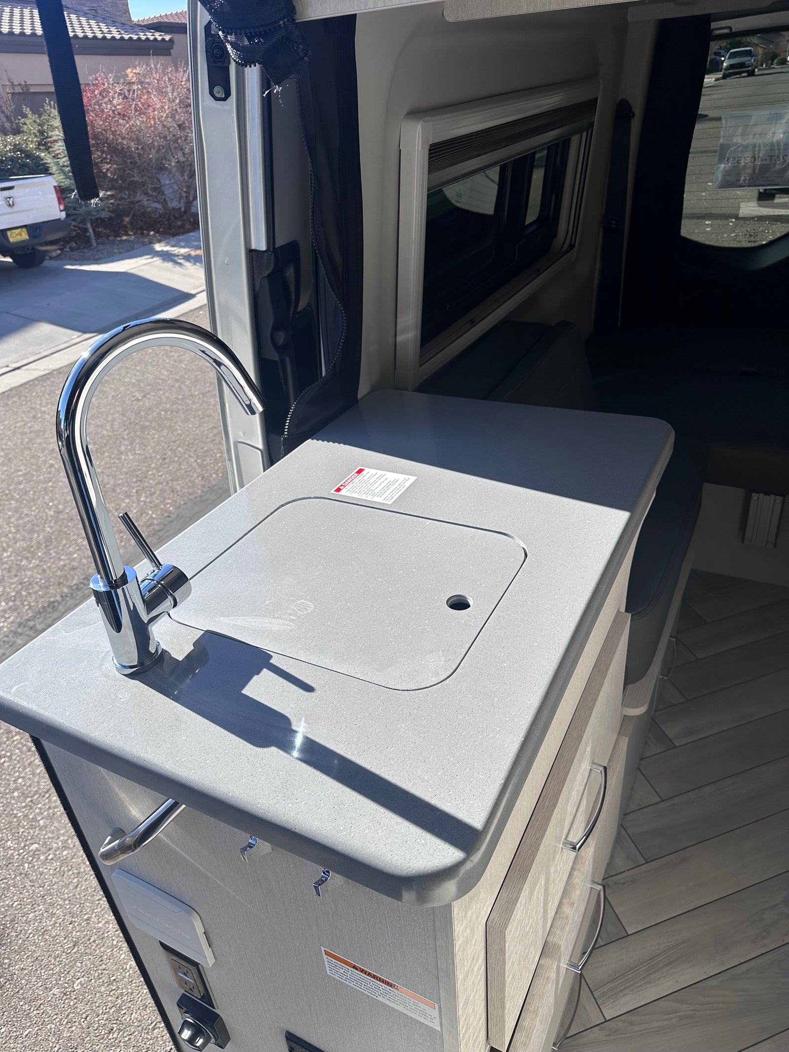 & digital dash.|RV rental's side door reveals a compact kitchen with a sink