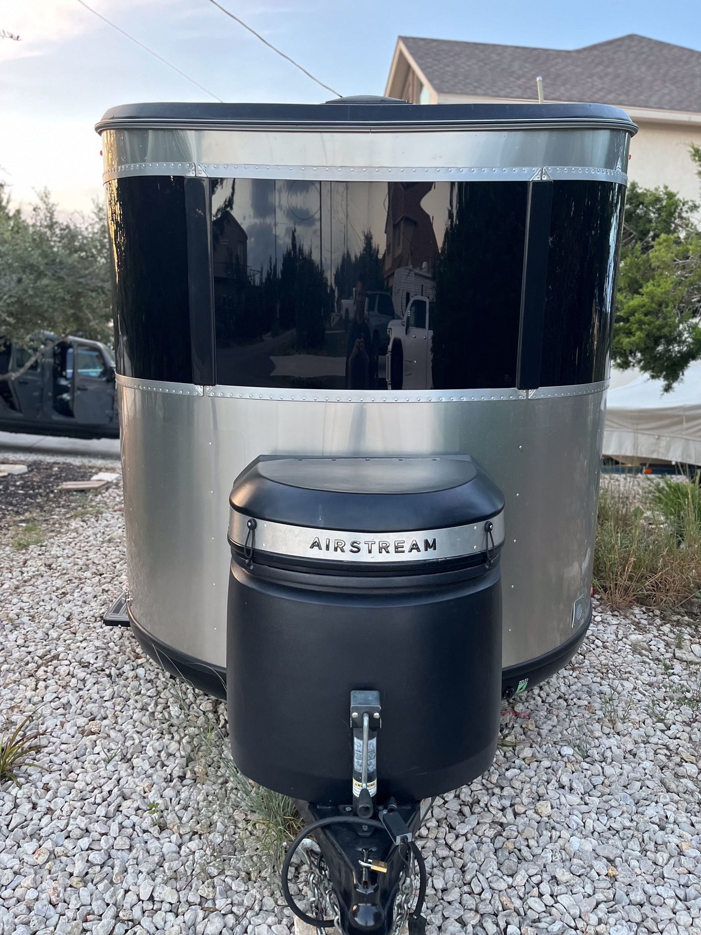 Sleek silver Airstream travel trailer with reflective black front, parked on gravel. Ideal for your next rv rental adventure.