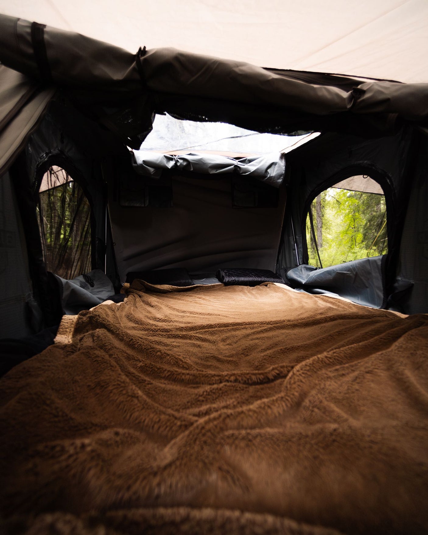 offering forest views. Ideal for your next RV rental trip.|Inside a cozy roof-top tent: grey sleeping area