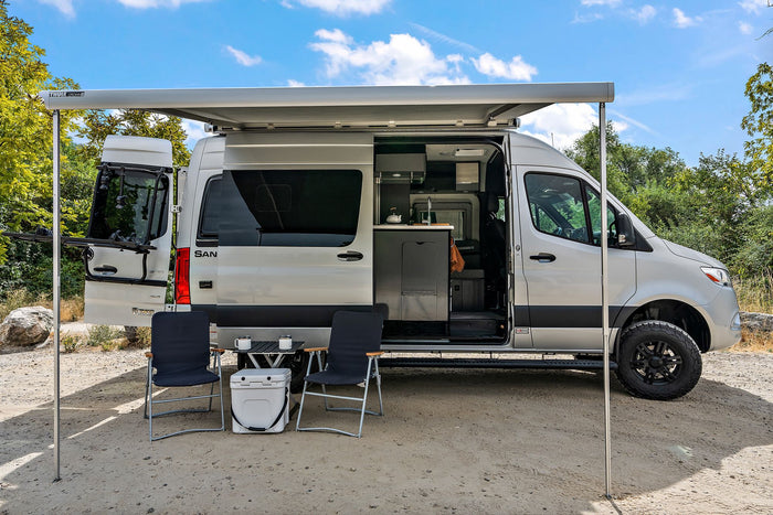 Silver Sprinter camper van rv rental with open doors, outdoor setup, and extended awning for adventure travel. Perfect for van life.