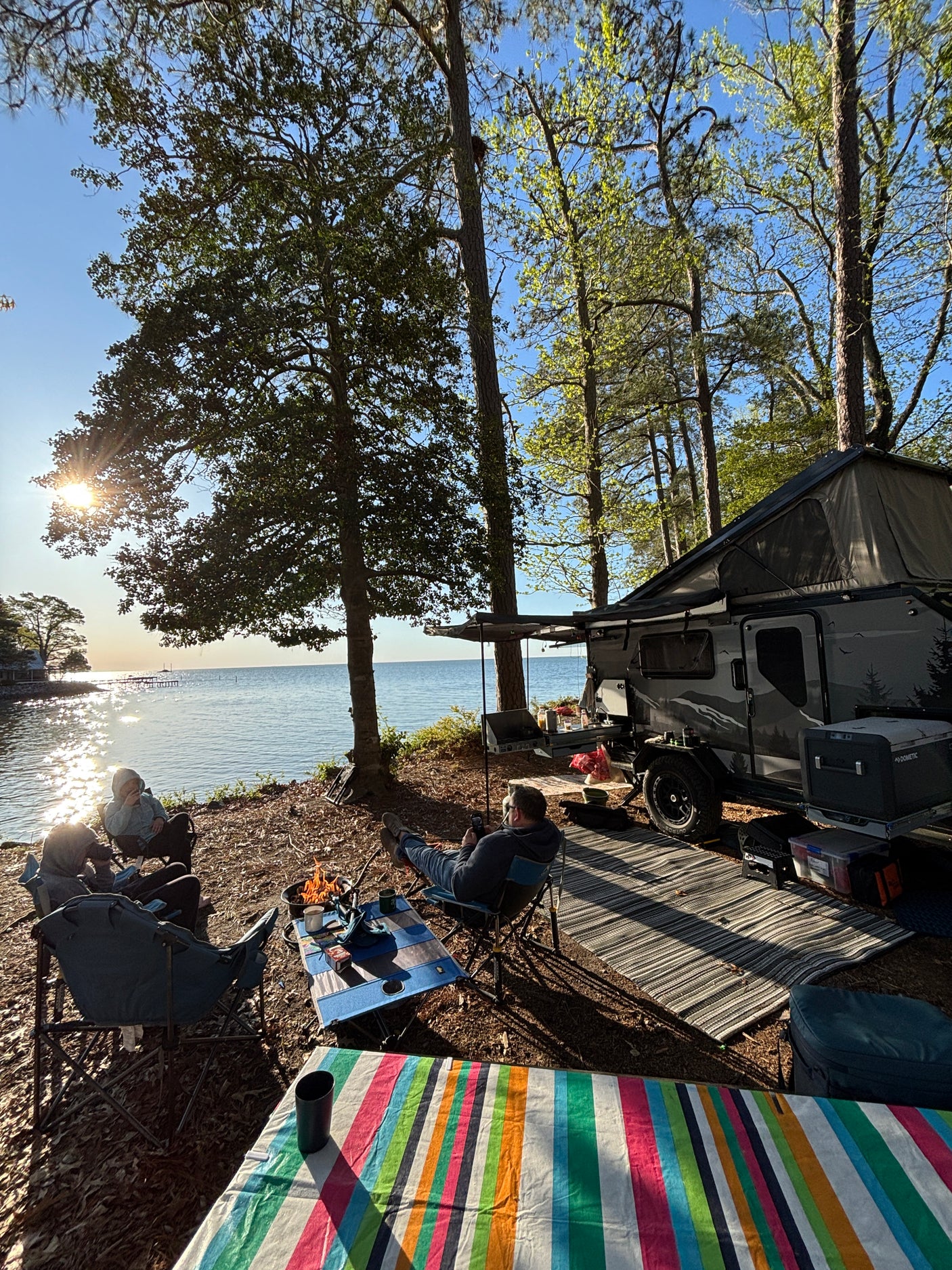 Lakeside RV rental camping with friends, a warm campfire, and beautiful sunset reflections over the water. Perfect outdoor escape!