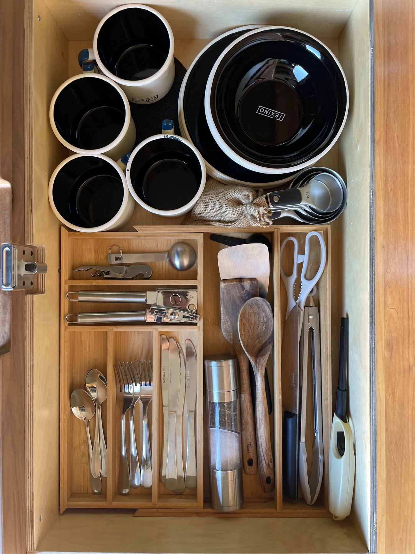 RV rental kitchen drawer: efficiently organized with mugs, bowls, cooking utensils, and silverware for your journey.