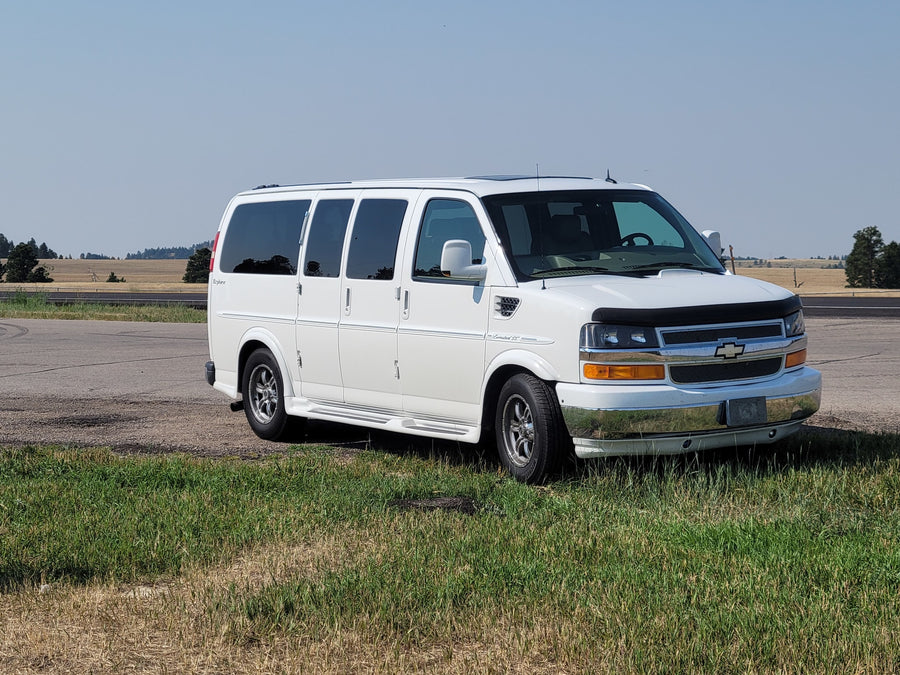 White Explorer conversion van parked on a grassy roadside
