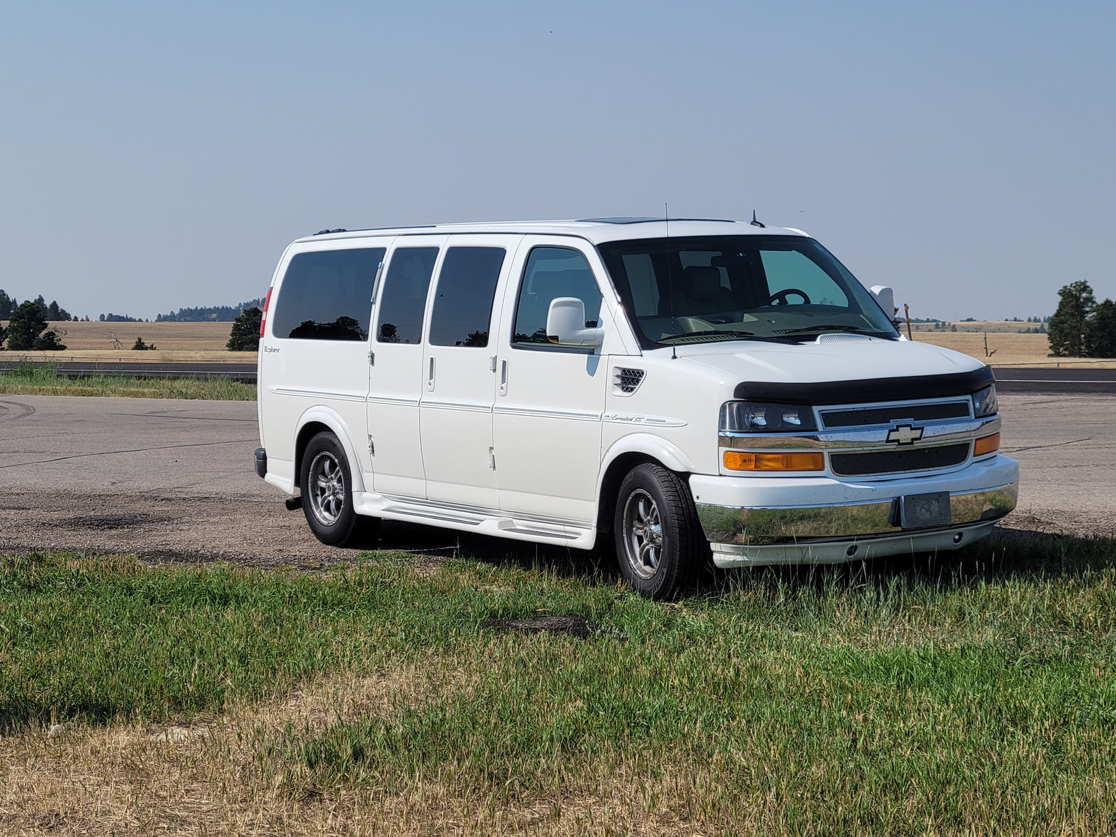 White Explorer conversion van parked on a grassy roadside