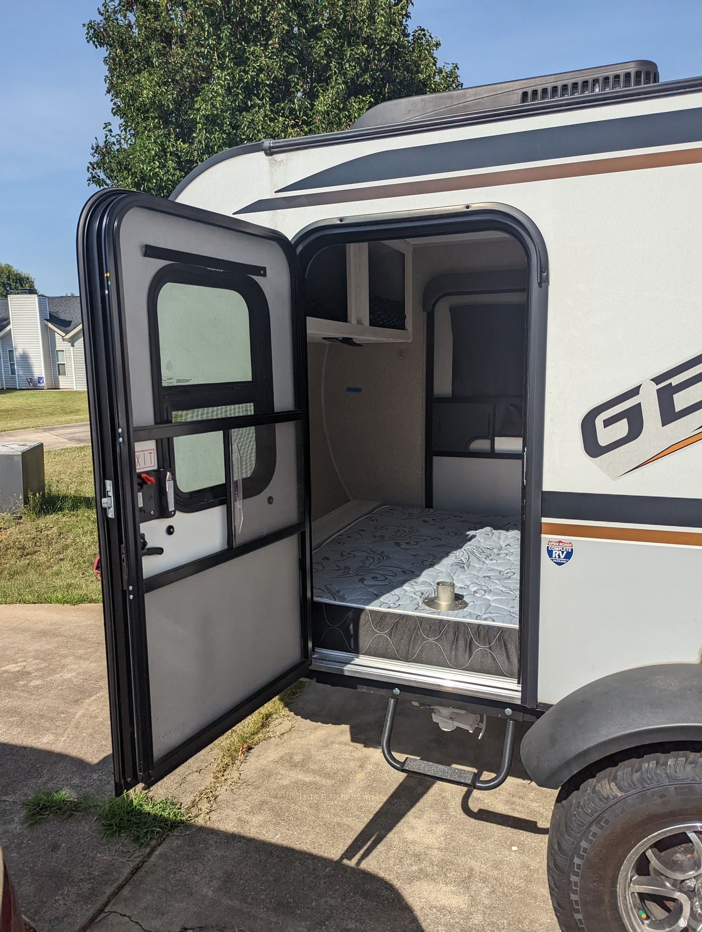 This rv rental, a compact travel trailer, welcomes you with its open door revealing a cozy bed for your next adventure.