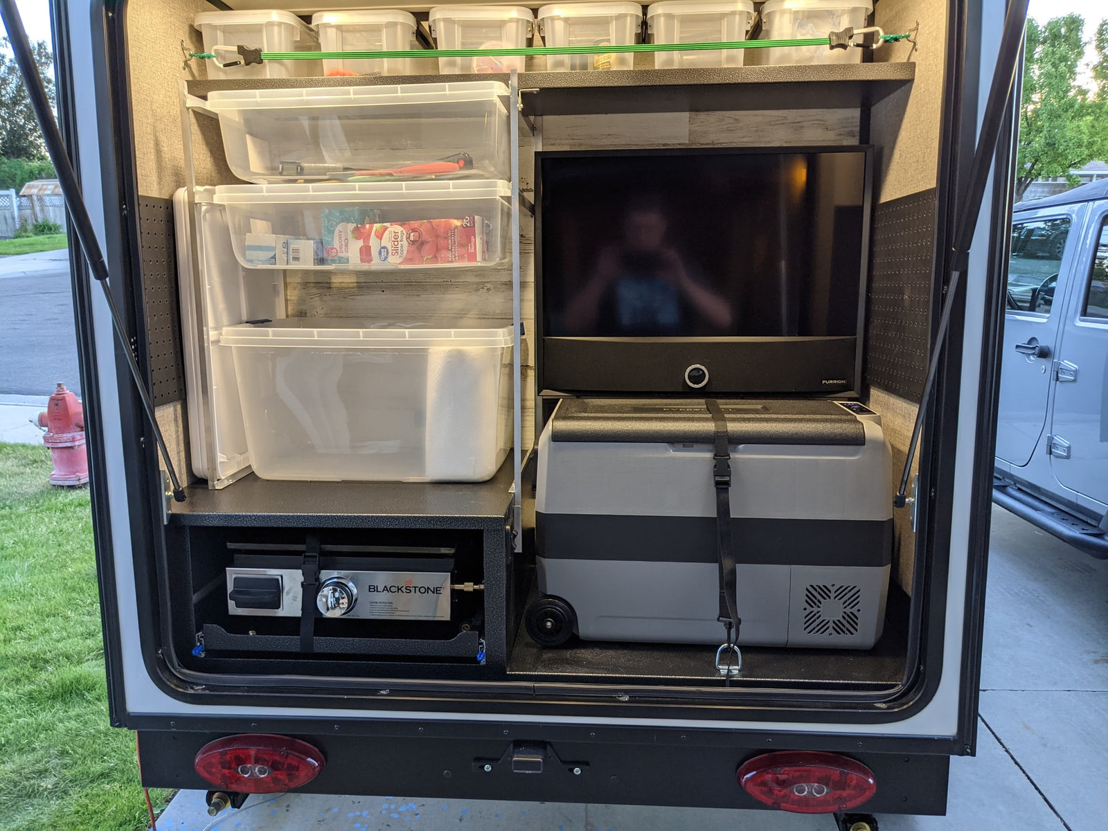 and tiered storage bins.|RV rental outdoor kitchen with a Blackstone griddle cooking bacon