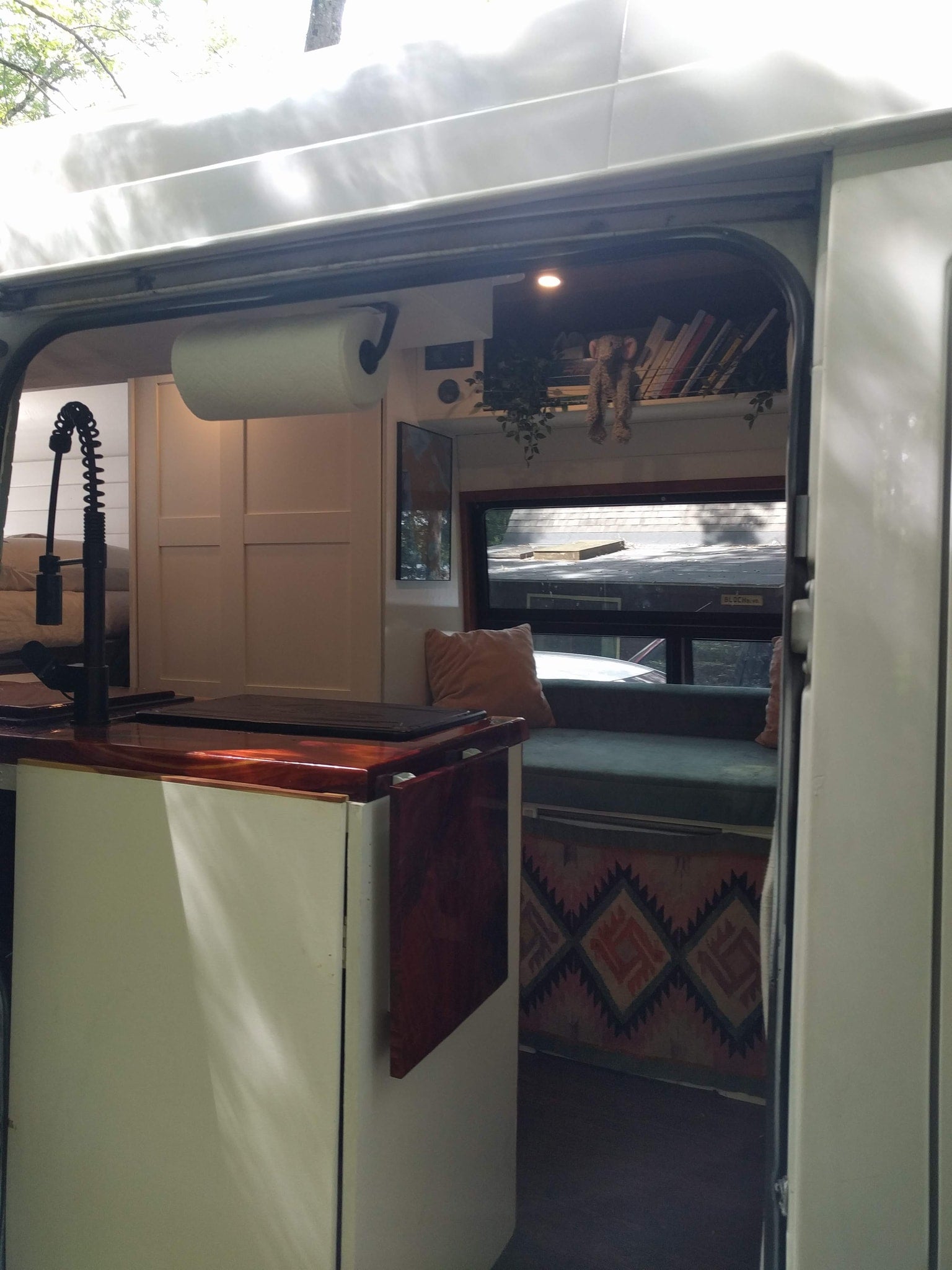 View inside this RV rental, featuring a functional kitchen area with a sink, a comfortable lounge, and ample storage.