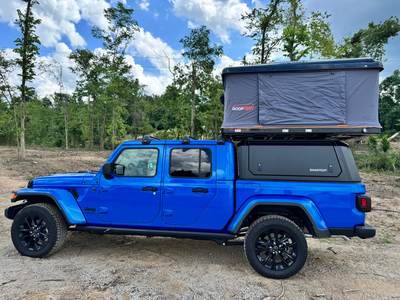 Bright blue Jeep Gladiator pickup with a SmartCap & Roofnest rooftop tent, ideal for your next rv rental adventure.