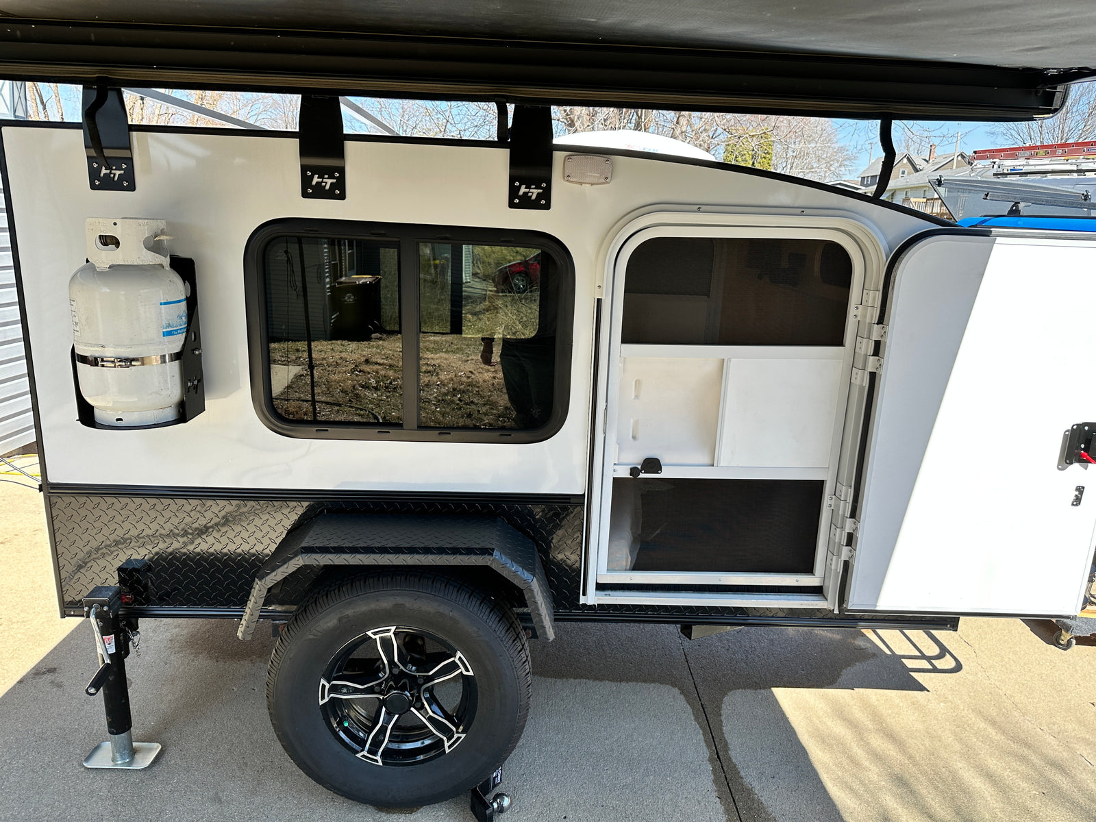 ready for adventure. Features an awning and front cargo rack.|White Hiker Trailer compact RV rental with roof awning