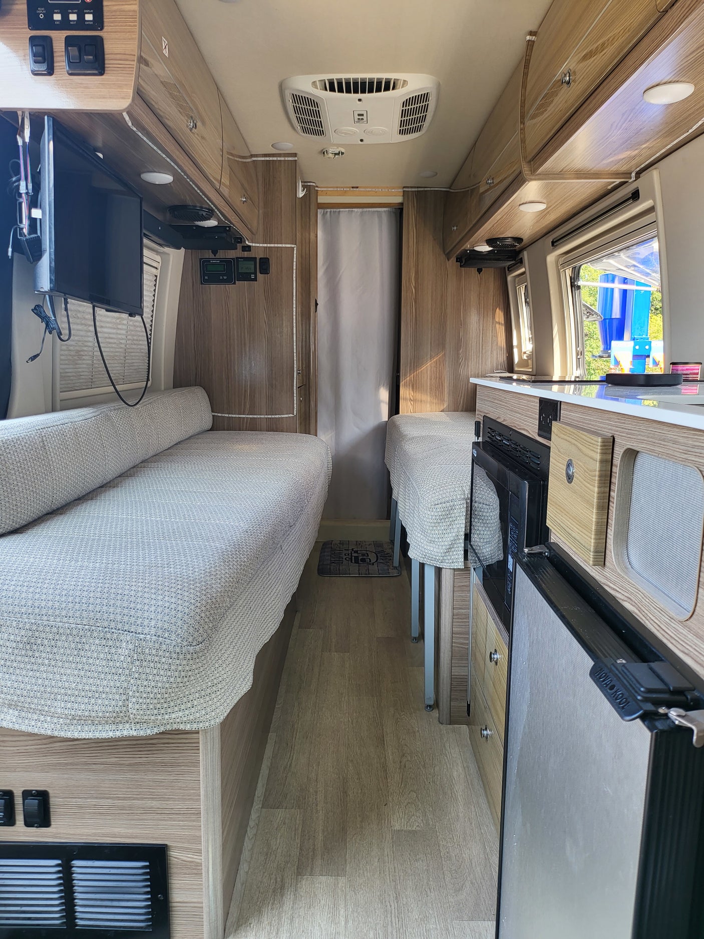 Explore this cozy rv rental interior featuring twin beds, a compact kitchen, and efficient storage solutions.