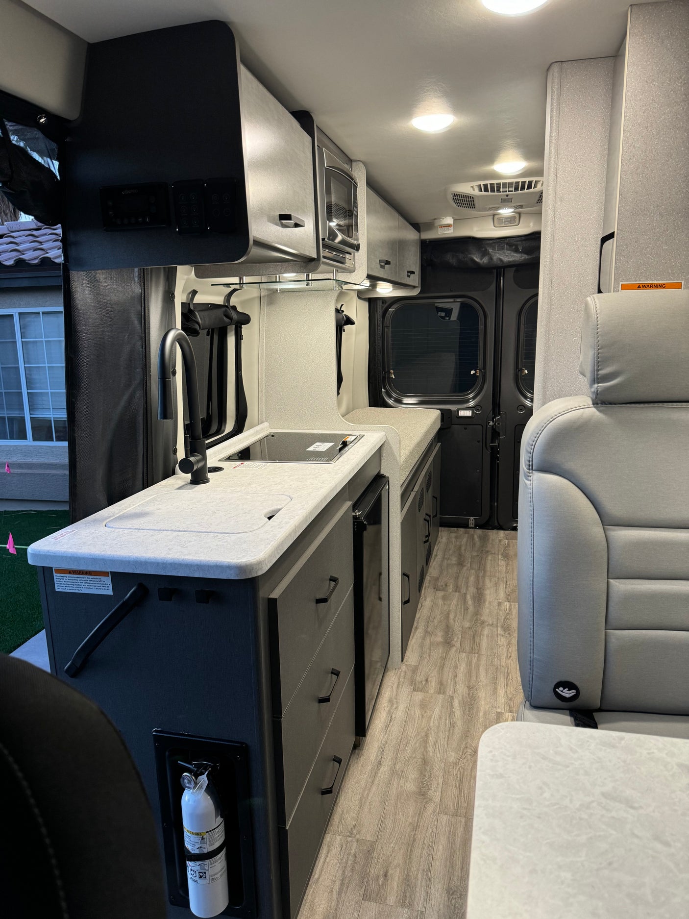 Explore this modern RV rental interior featuring a compact kitchen, sink, stove, microwave, and cozy living space.