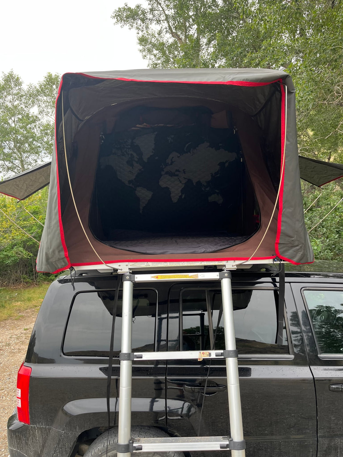 a world map design awaits for your next car camping trip.|Black SUV with iKamper roof-top tent set up for camping. Great rv rental alternative for outdoor adventures. — photo 5