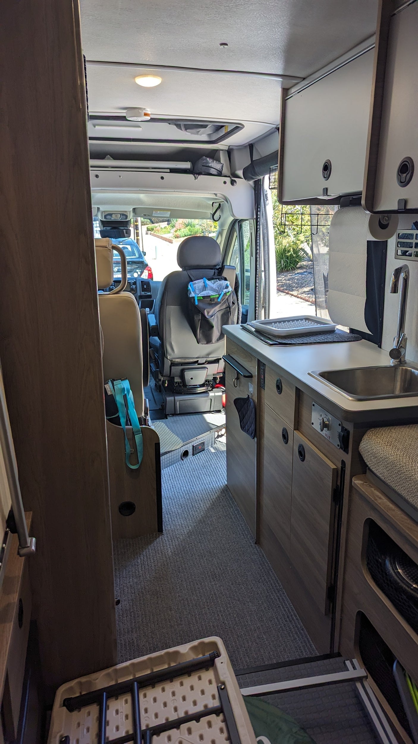 Inside an RV rental: a compact kitchen with sink and counters, looking towards the driver's area, perfect for travel.