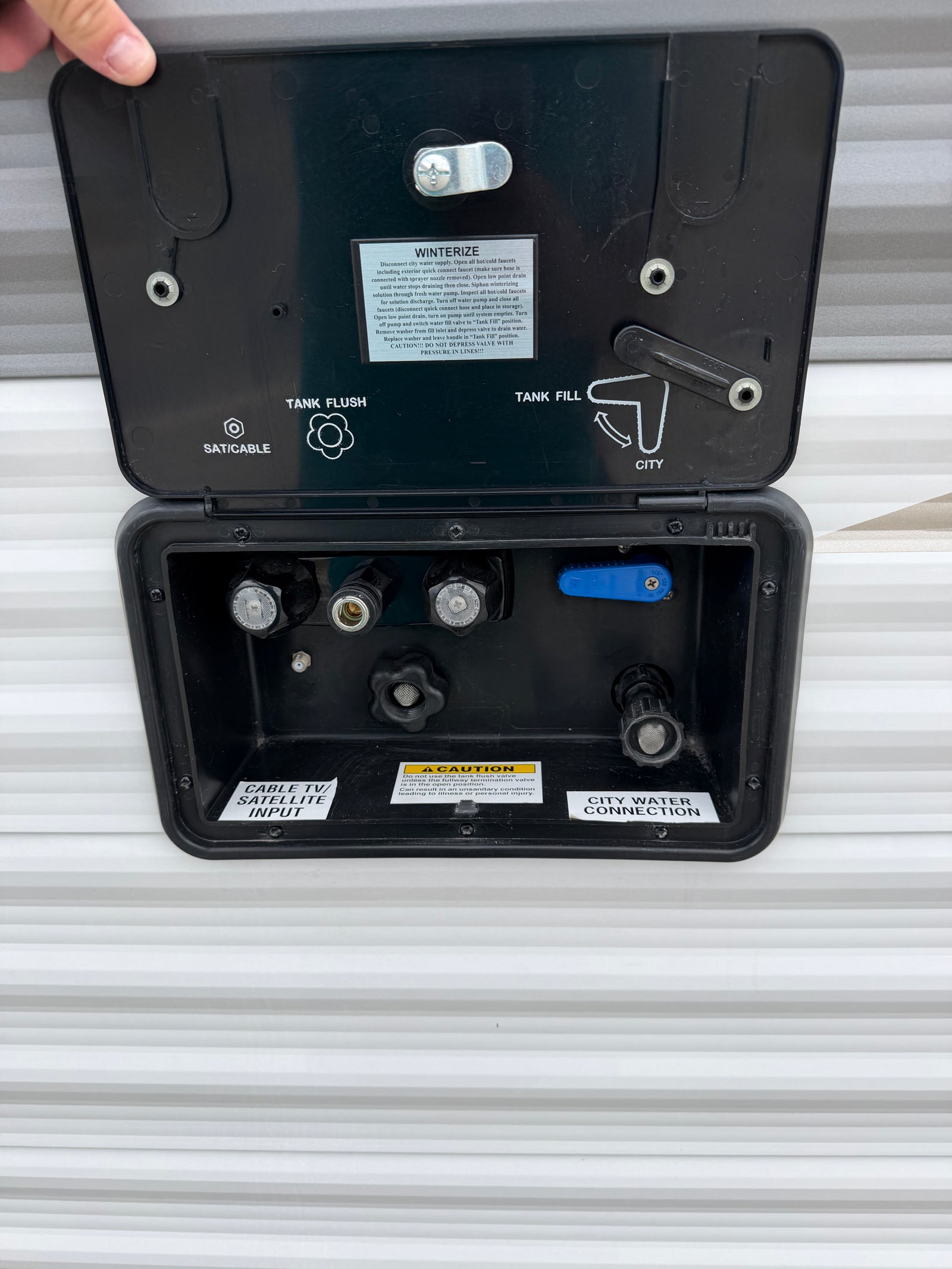 RV rental utility panel: connections for city water, tank fill/flush, winterization, and cable/satellite inputs.