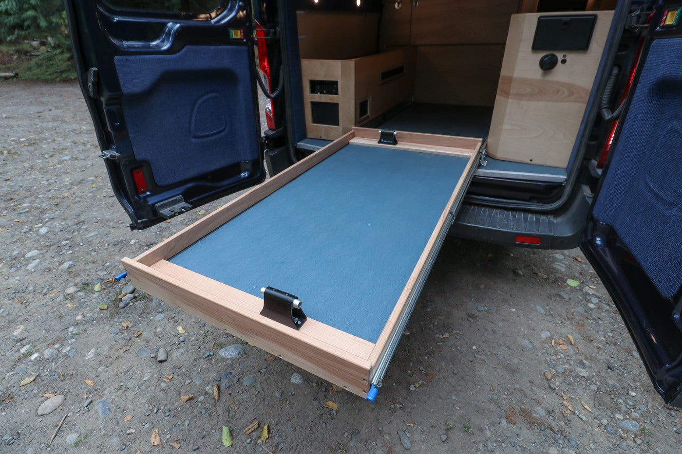 This RV rental's van conversion reveals a spacious pull-out cargo tray with a bike fork mount for gear.