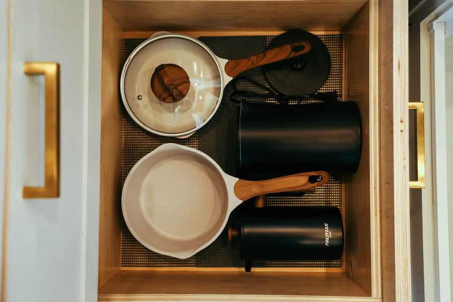Compact kitchen storage in an RV rental: organized pots, pans, and small appliances in a wood drawer.
