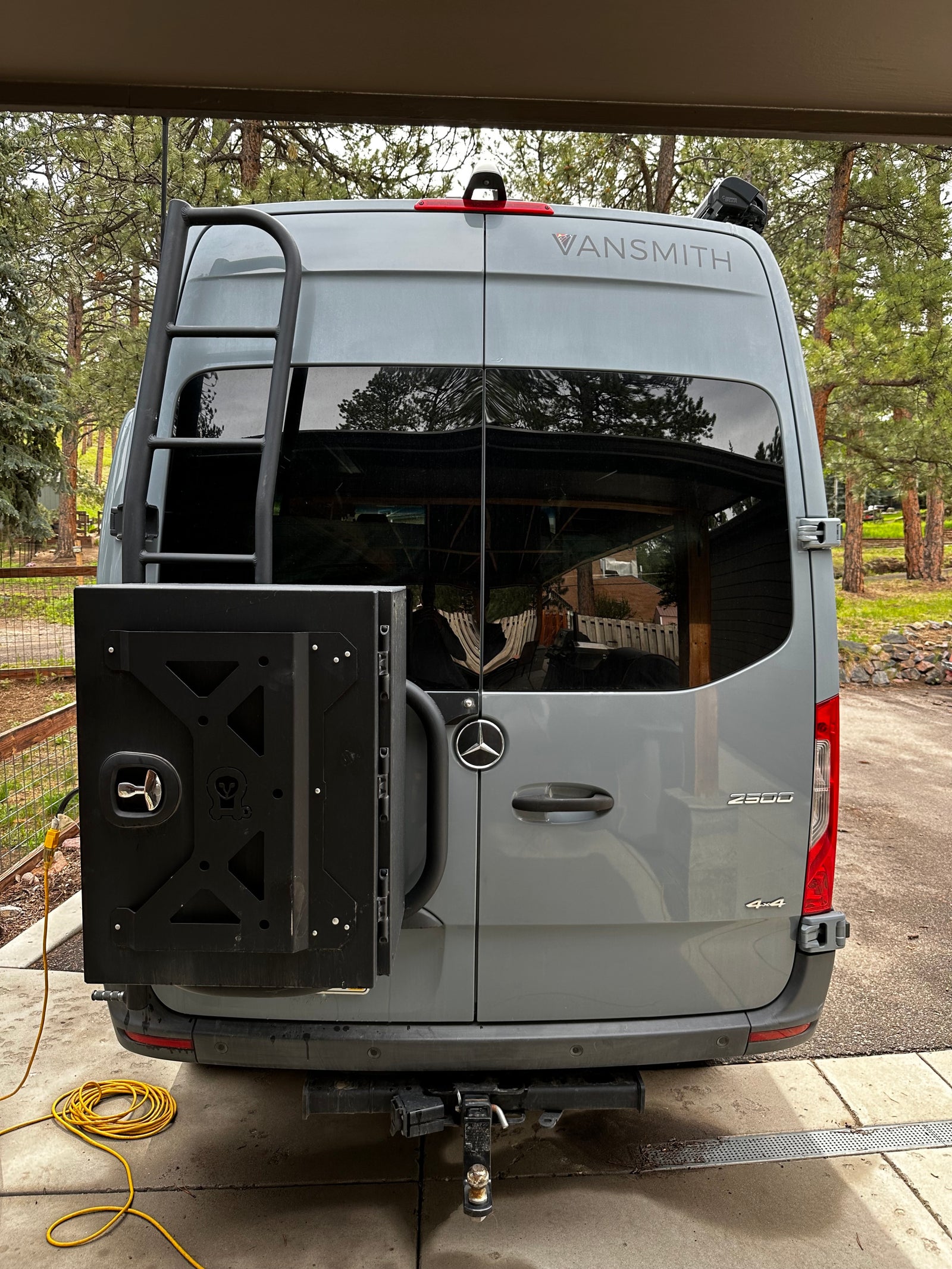 A gray Mercedes-Benz Sprinter RV rental's rear, featuring a ladder, cargo box, and tow hitch for adventures.