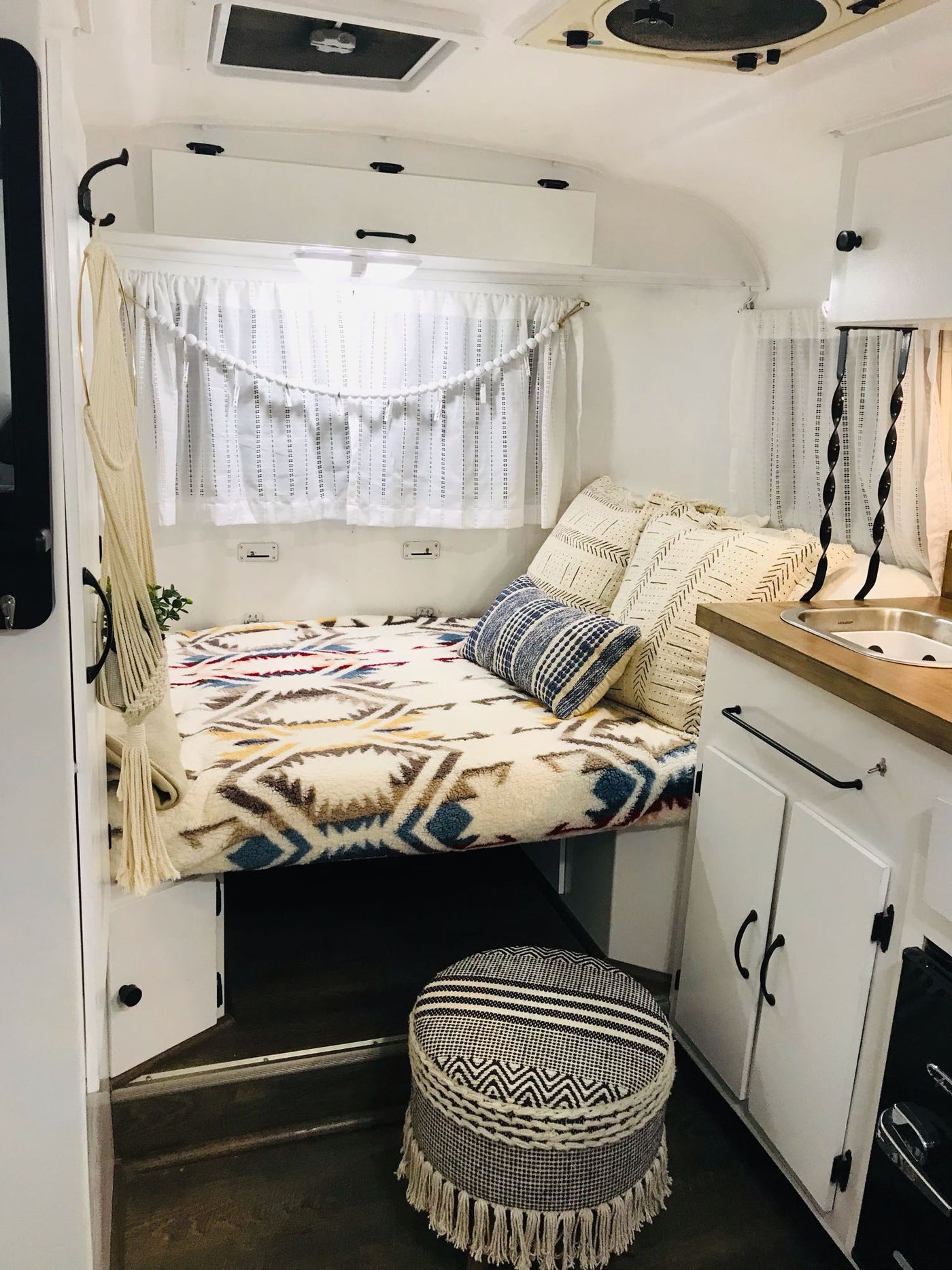 and a stylish sleeping nook.|Bright RV rental kitchen with white cabinets — photo 9