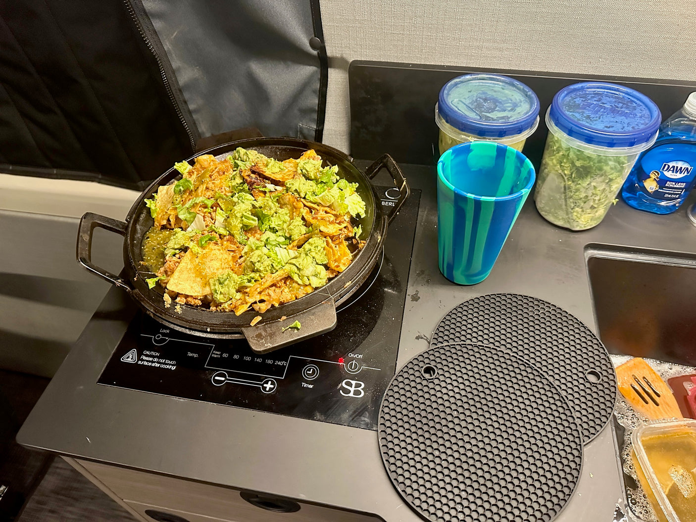 Cooking delicious nachos on a portable induction cooktop in an RV rental! Compact kitchen with dish soap & soaking dishes.