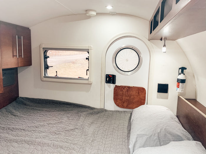 is hitched to an SUV in a sunny parking lot.|Explore this RV rental's clever rear outdoor kitchen
