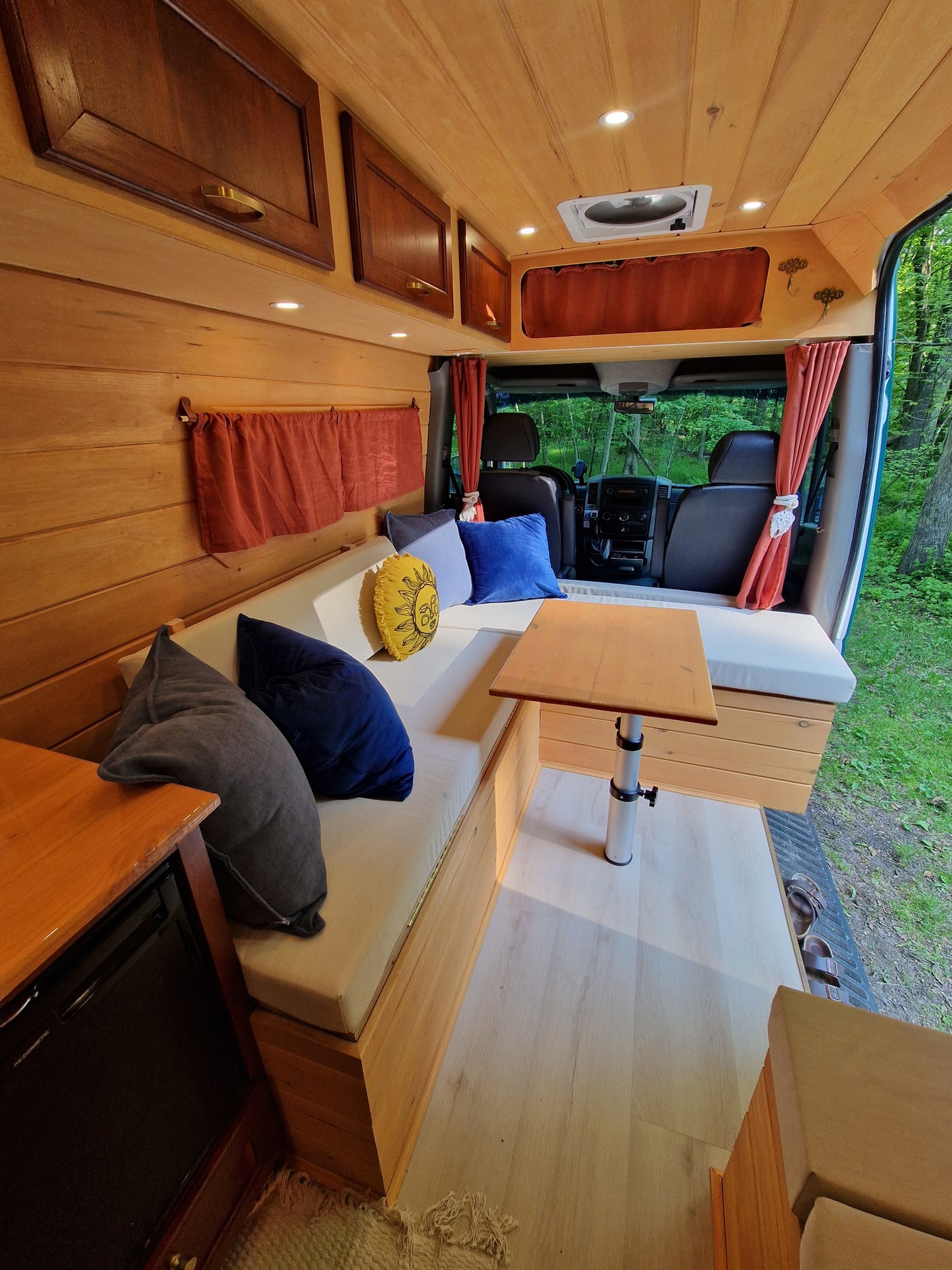 Cozy RV rental interior with wood paneling, cushioned seating, and adjustable table, perfect for mobile adventures.