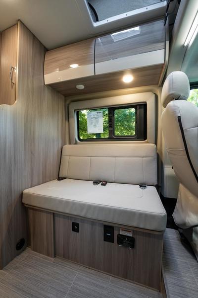 and window.|Inside an RV rental: cozy cream-colored dinette seating with under-bench storage