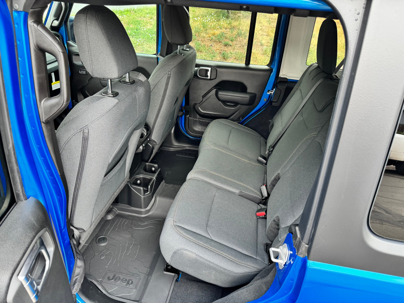 Clean rear interior of a blue SUV with fabric seats & all-weather floor mats, ideal for an RV rental road trip.