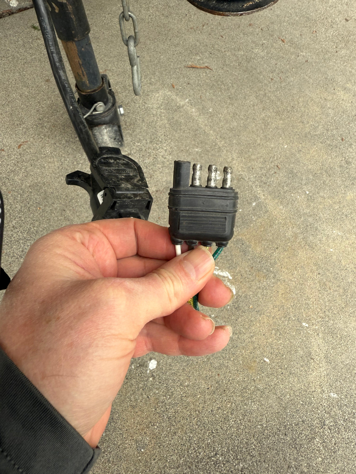 A person's hand holds a 4-pin trailer light connector, crucial for safe RV rental towing and trailer hookup. — photo 14