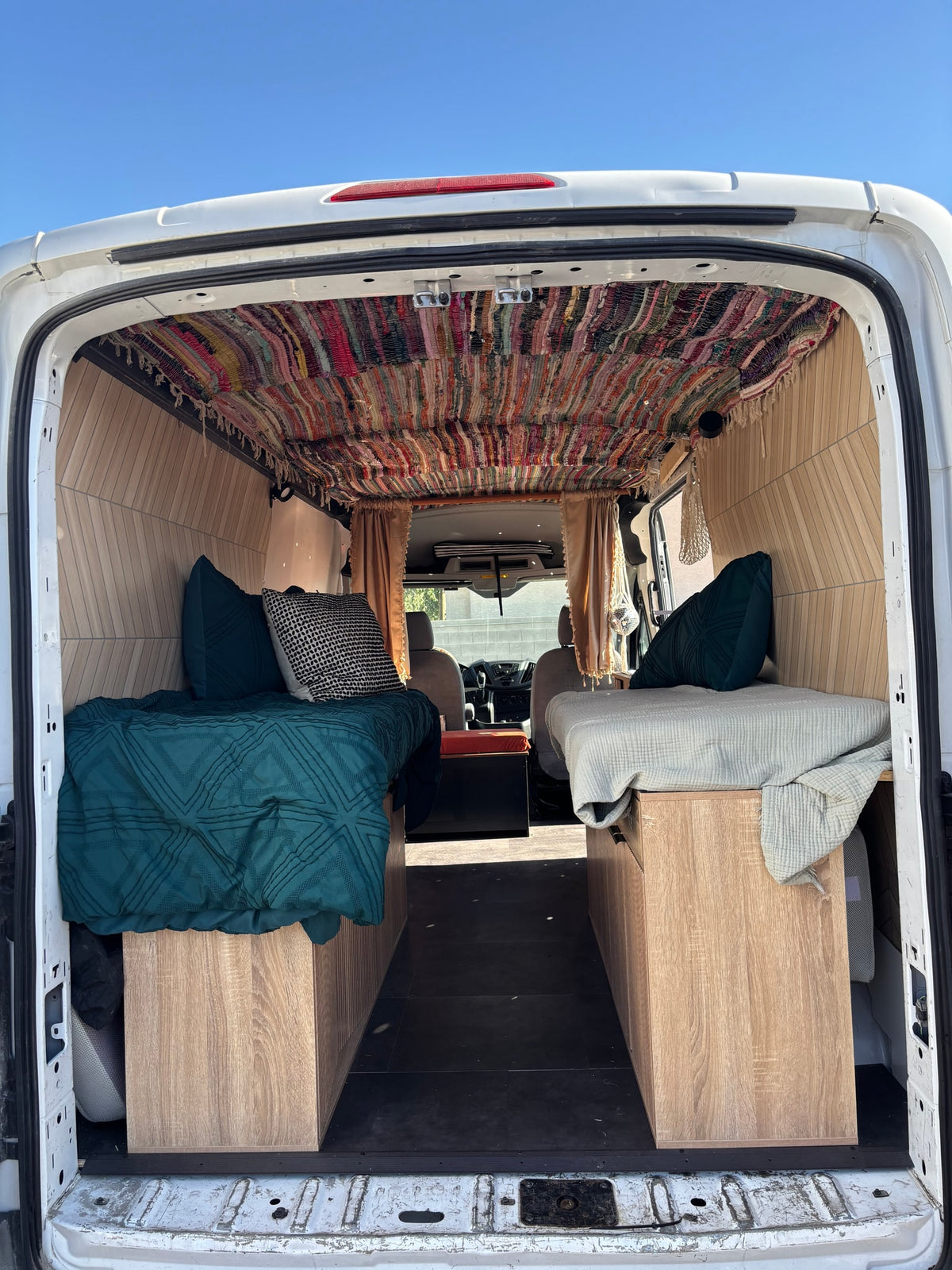 Explore this charming rv rental! A customized camper van interior features two beds, a unique colorful woven ceiling, & wood details. — photo 8
