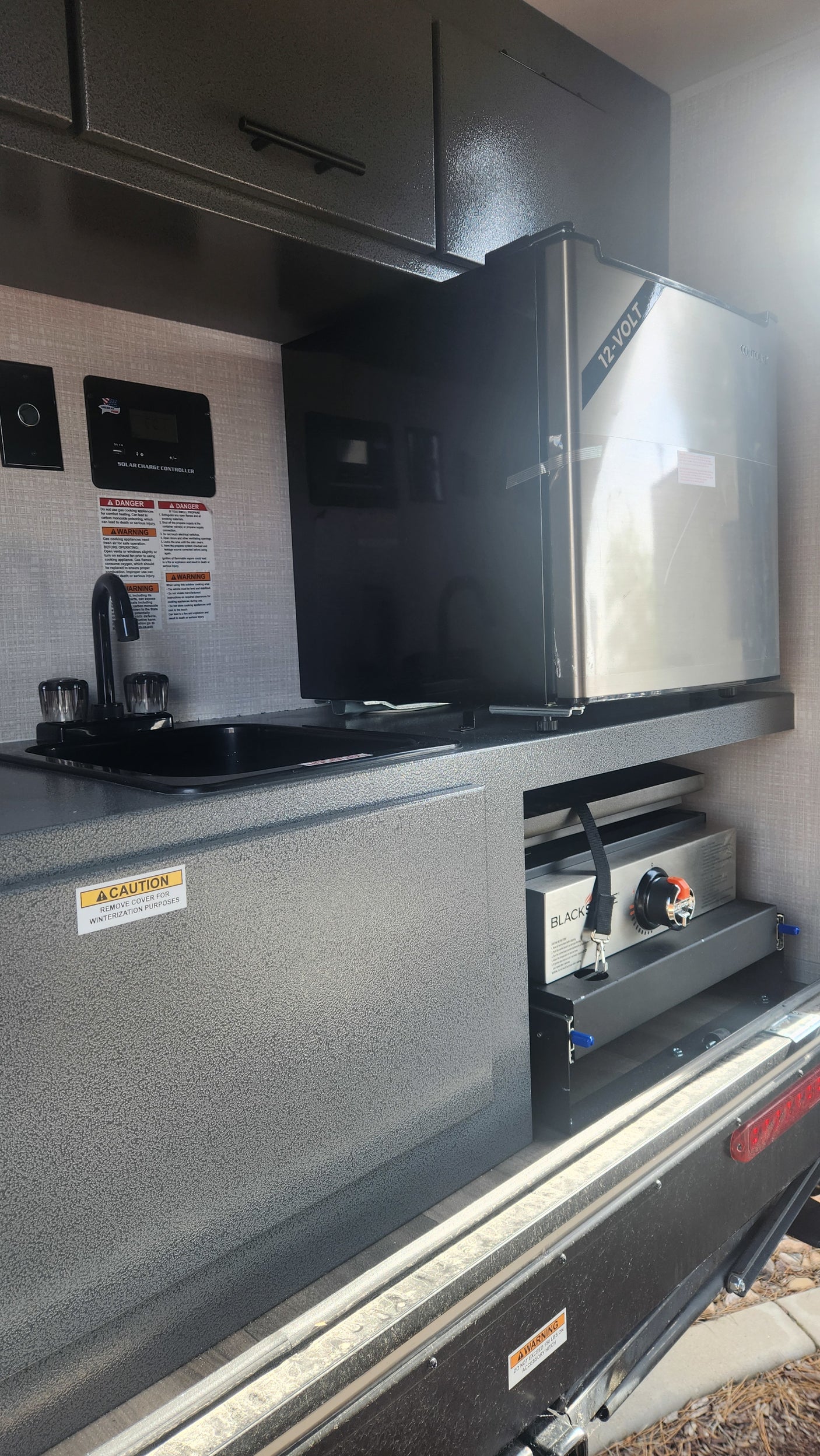This rv rental boasts an outdoor kitchen, featuring a sink, 12-volt fridge, and a pull-out Blackstone griddle.