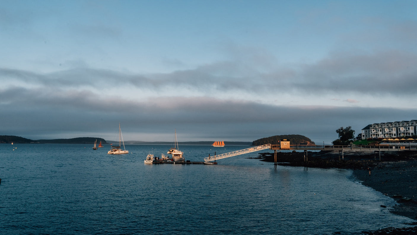 Twilight coastal harbor: boats, long pier, & waterfront resort. A scenic travel destination. Consider an RV rental trip!