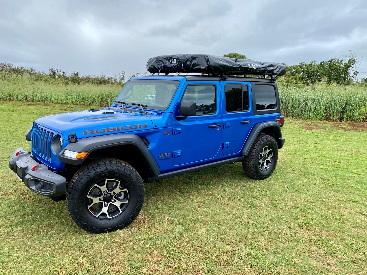This blue Jeep Wrangler Rubicon with a rooftop tent is an ideal RV rental for off-road adventures.
