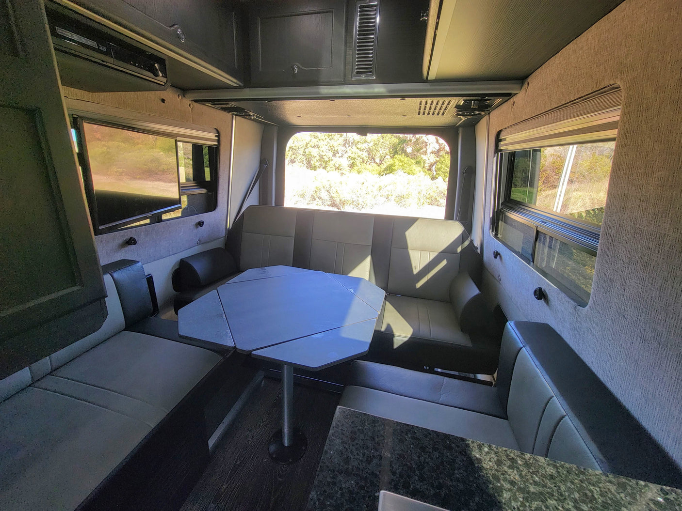 RV rental interior: versatile seating & dining area, entertainment system, and scenic windows for comfortable travel.