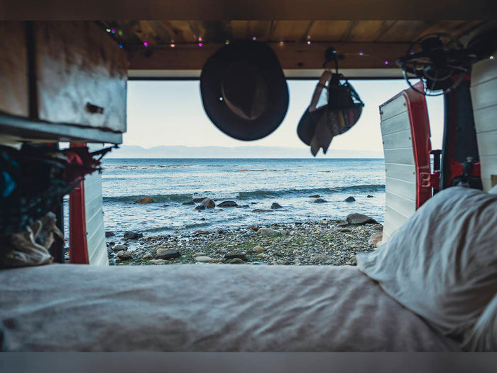 and bed. Perfect mobile living.|RV rental interior: A gear-filled tactical seat organizer hangs on a swiveled seat; a complex seat base optimizes space.|View from inside an RV rental shows a bed in foreground