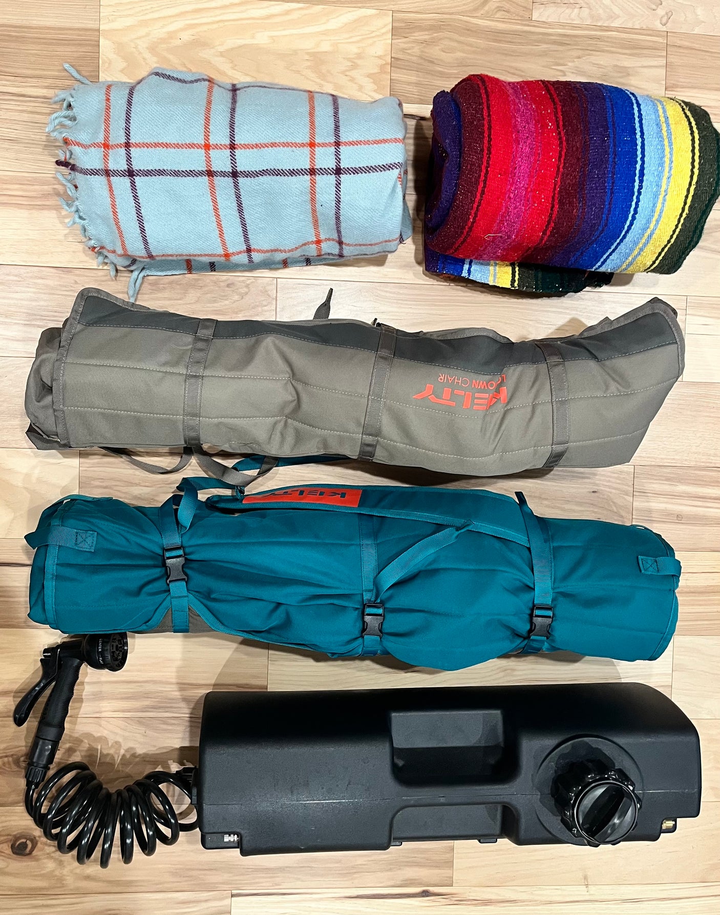 RV rental essentials: Cozy blankets, two rolled Kelty camp chairs, and a portable water system for outdoor adventures.