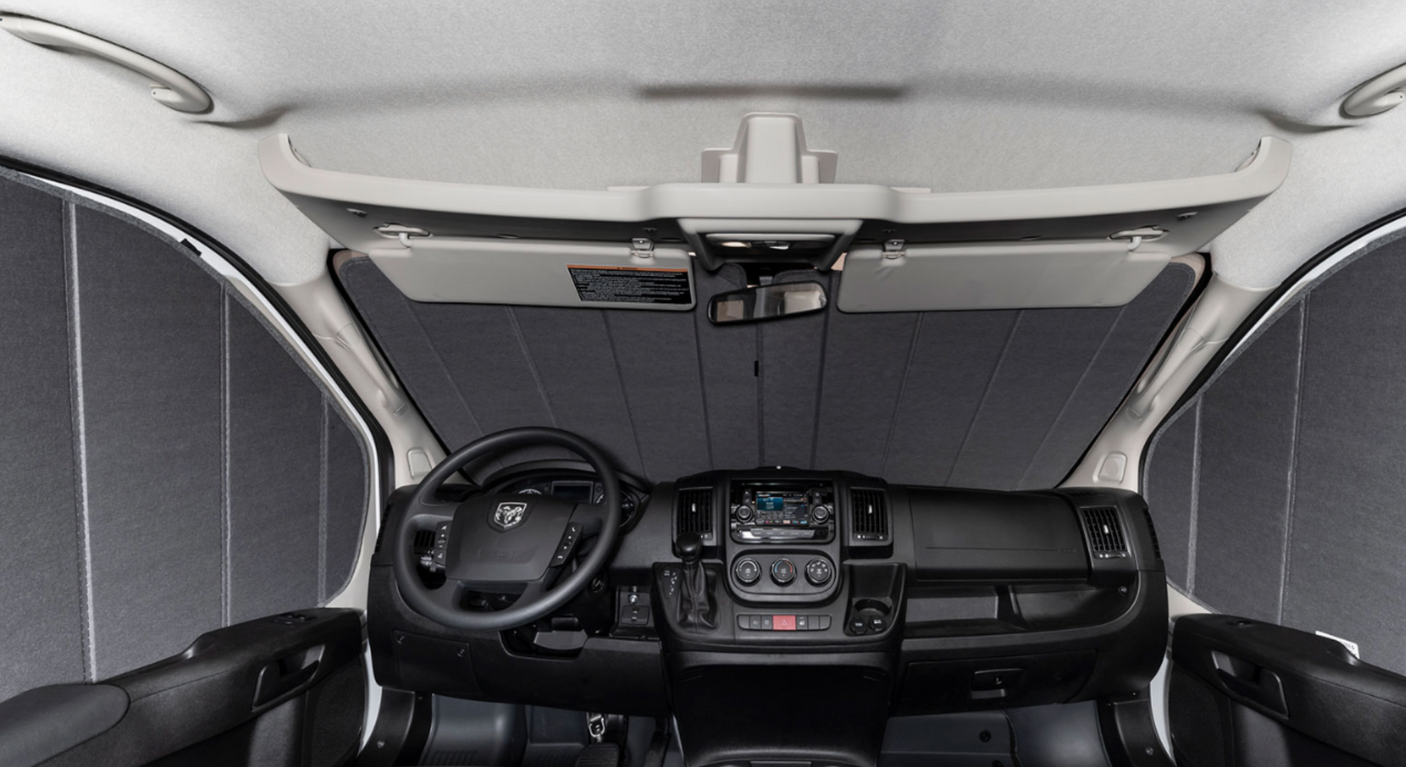 RV rental front cab interior with privacy shades deployed, showing the dashboard, steering wheel, and overhead console.