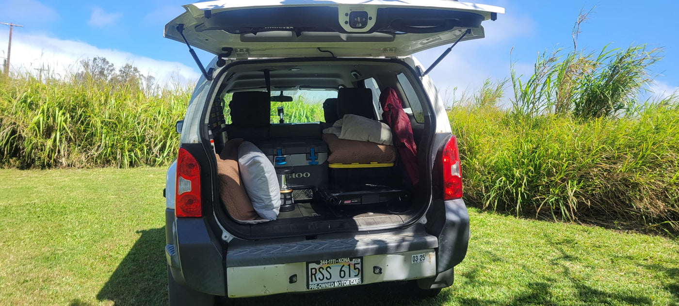White SUV tailgate open, packed with camping gear (cooler, pillows, stove). Great for an RV rental style outdoor getaway. — photo 6