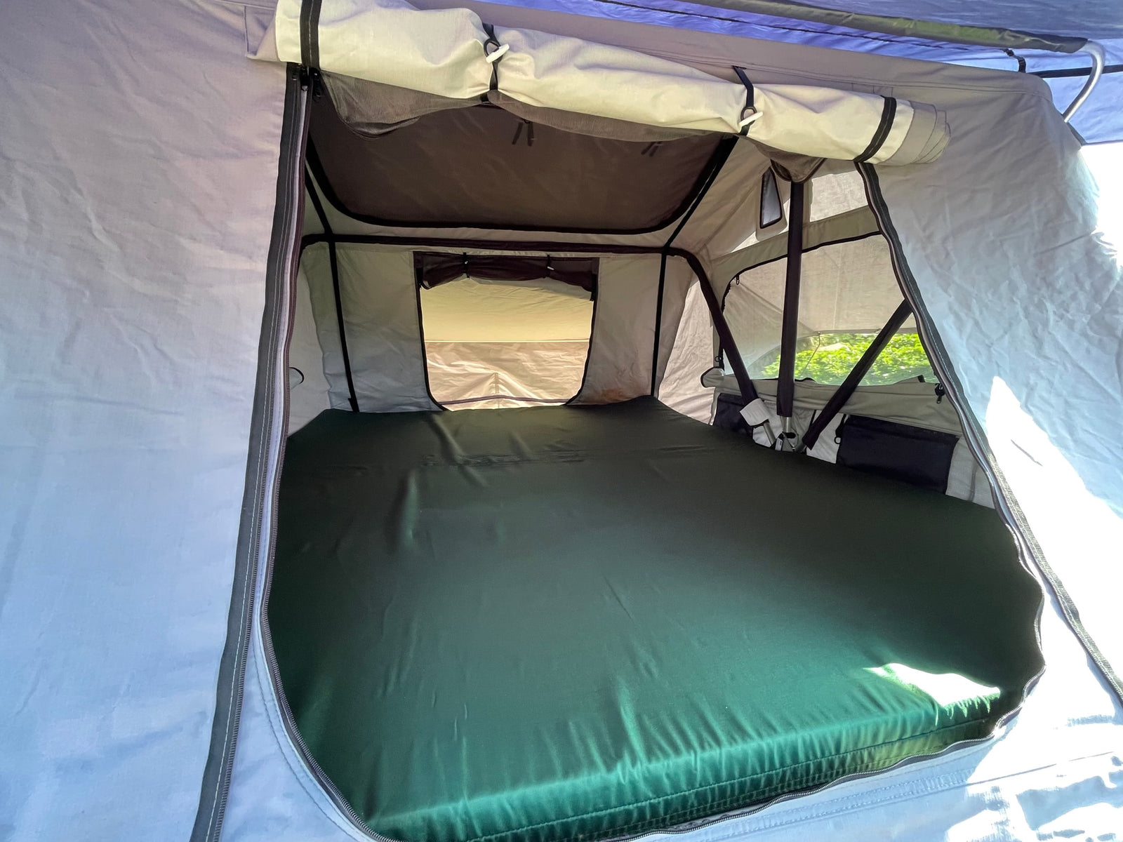 View inside a spacious camping tent with a large green mattress. Ideal for outdoor adventures or your next RV rental excursion.