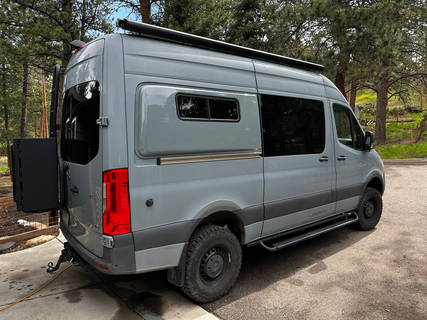 Gray Sprinter **rv rental** by VANSMITH. This adventure van features off-road tires, an awning, and rear storage.