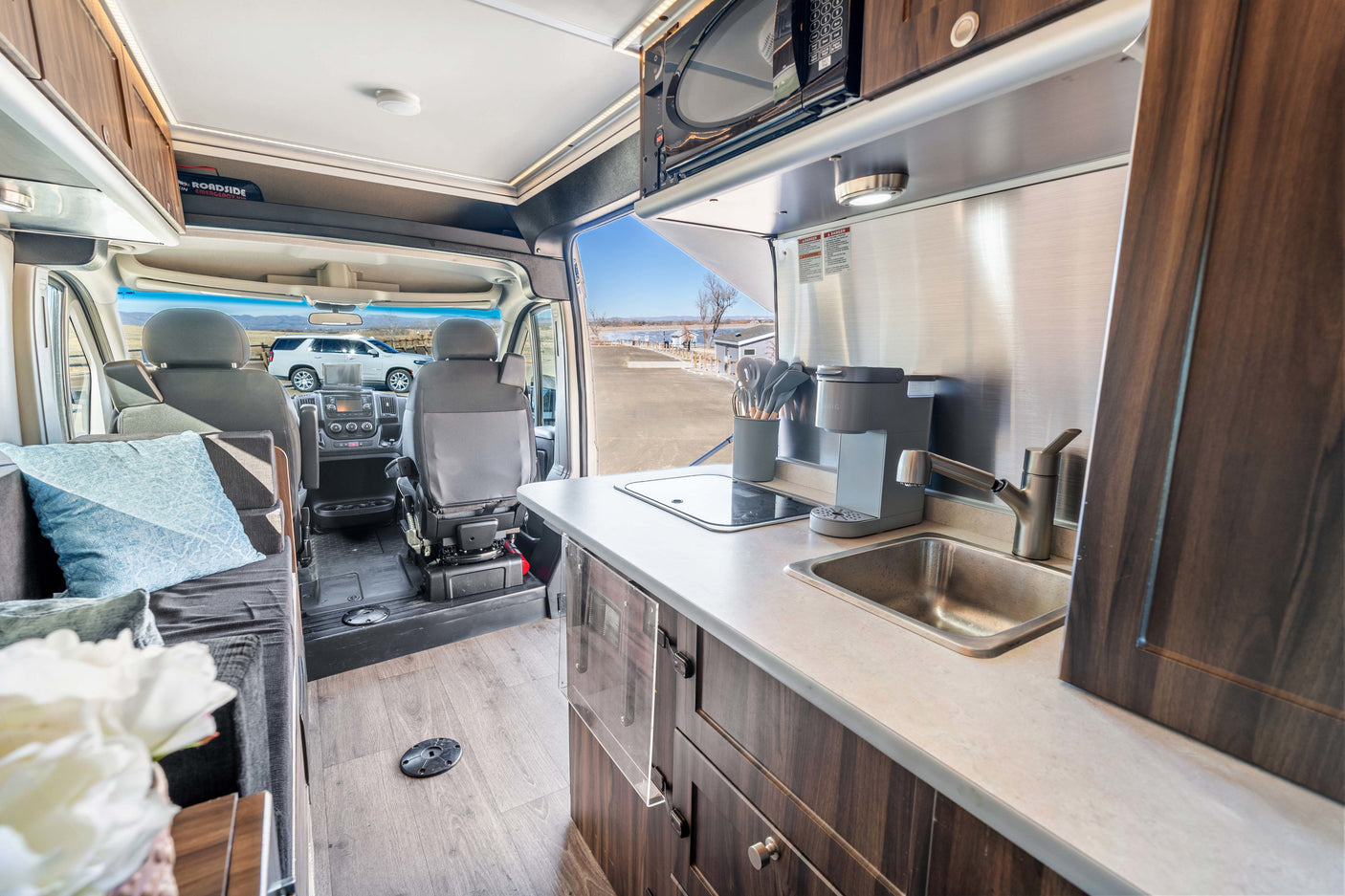 Explore this well-equipped RV rental interior with a compact kitchen, lounge, and scenic view out front.