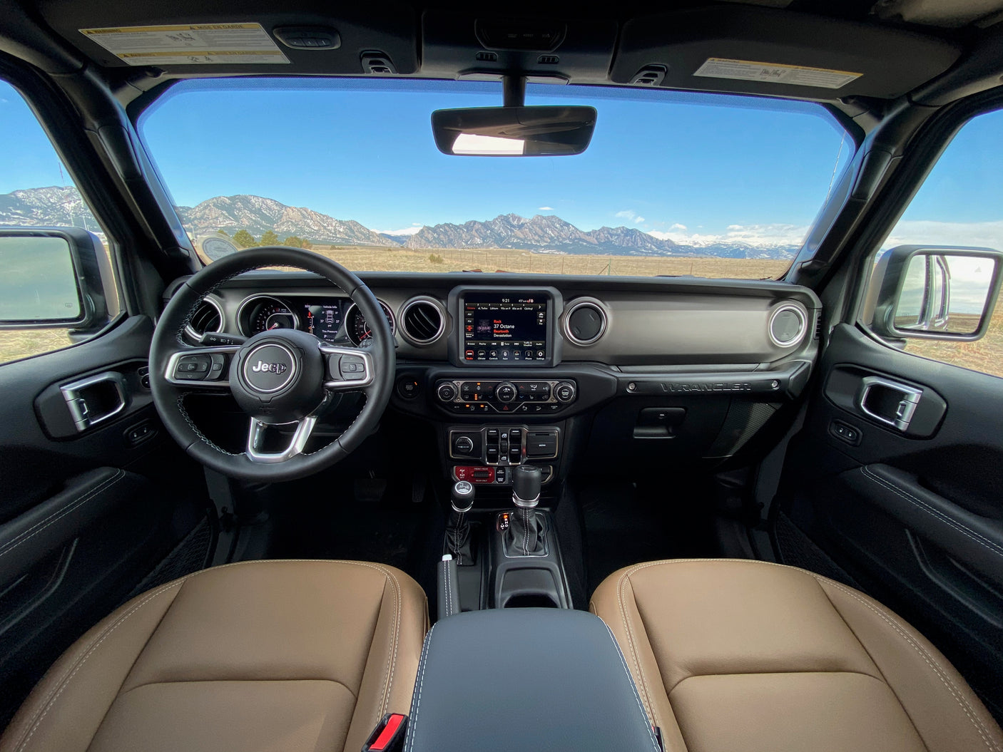 Jeep Wrangler interior with mountain vista, perfect for outdoor travel. More nimble than an rv rental for rugged terrain.
