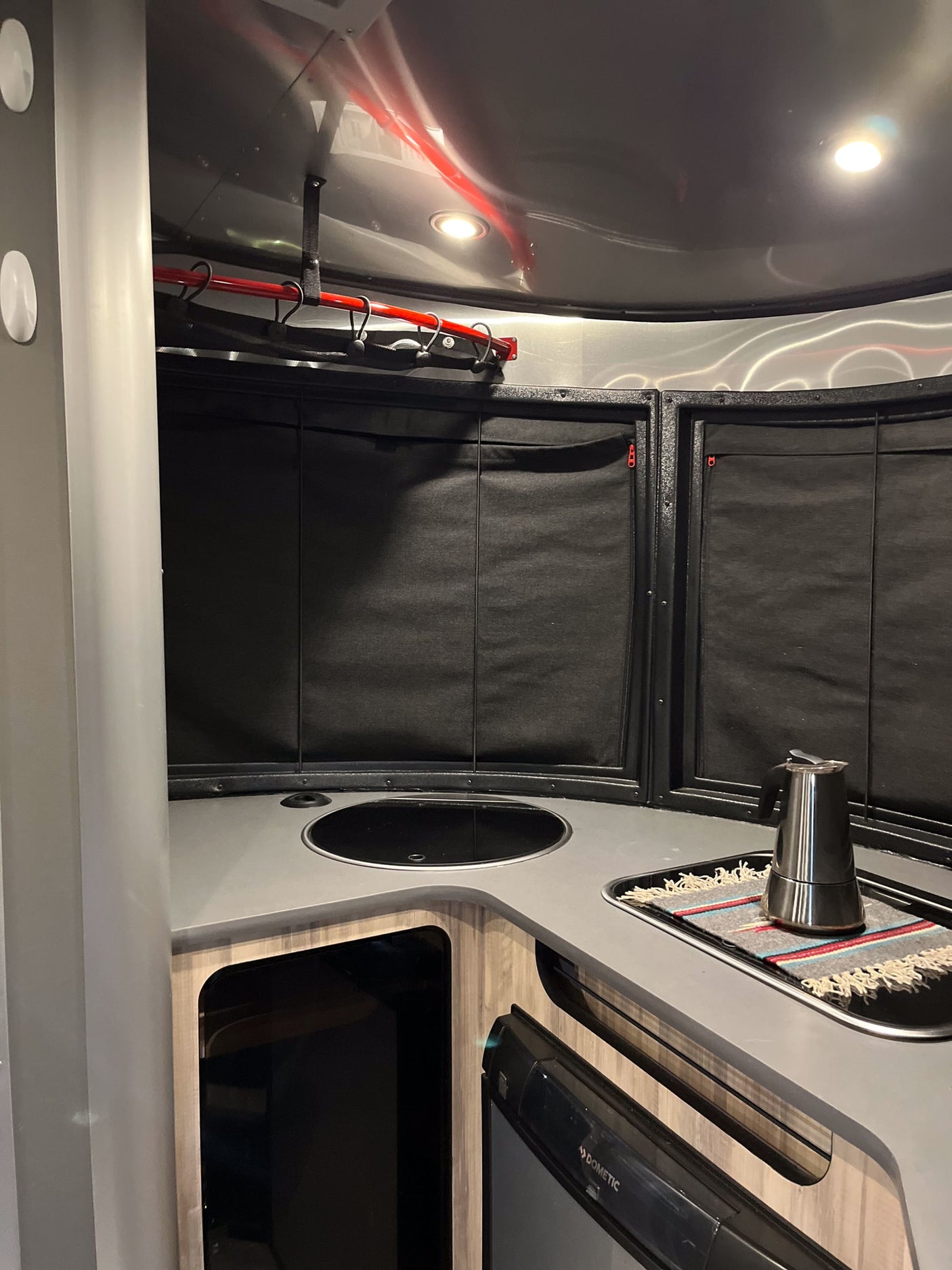 Modern RV rental kitchenette, showing a sink, coffeemaker on counter, and Dometic fridge below.