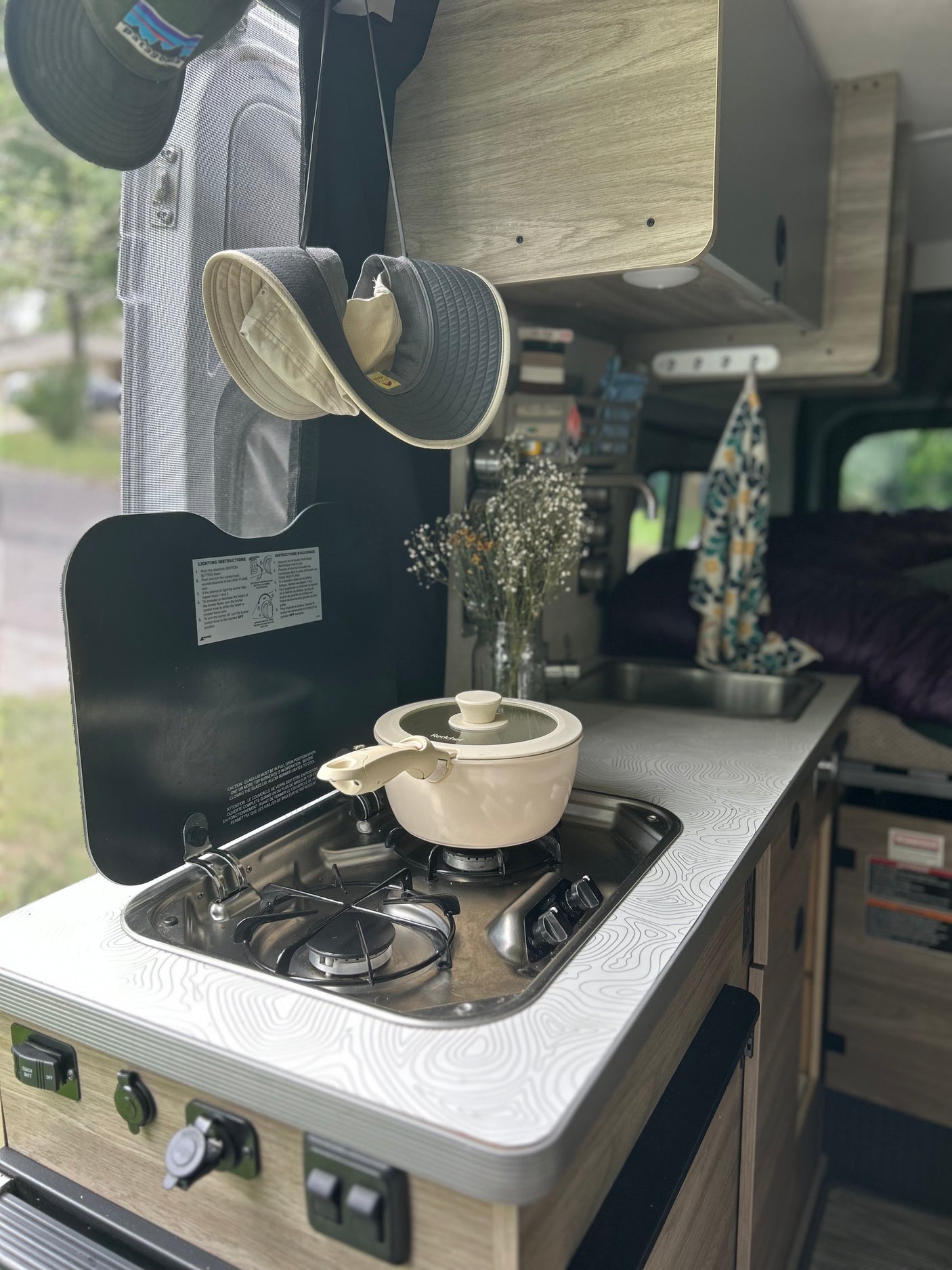 An RV rental's cozy kitchenette, featuring a pot on the stove, sink, and a unique topographic counter pattern.