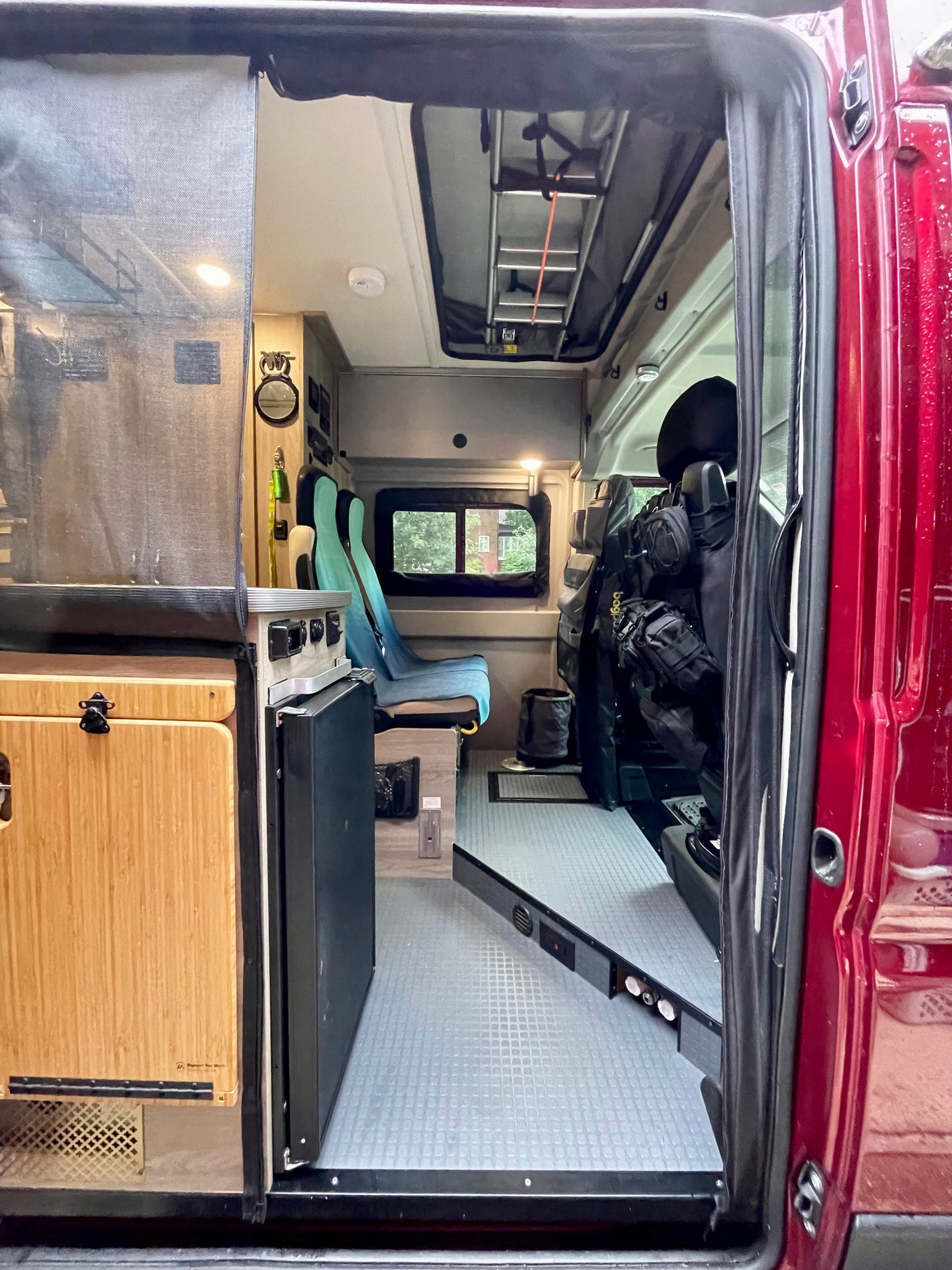 RV rental interior: a detailed view of a camper van's smart design, with modular seating, bamboo kitchen, and overhead storage.