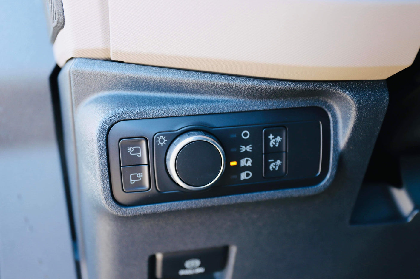 RV rental interior: Close-up of vehicle dashboard with headlight rotary dial (set to 'headlights on'), fog light buttons, and dash dimming controls.