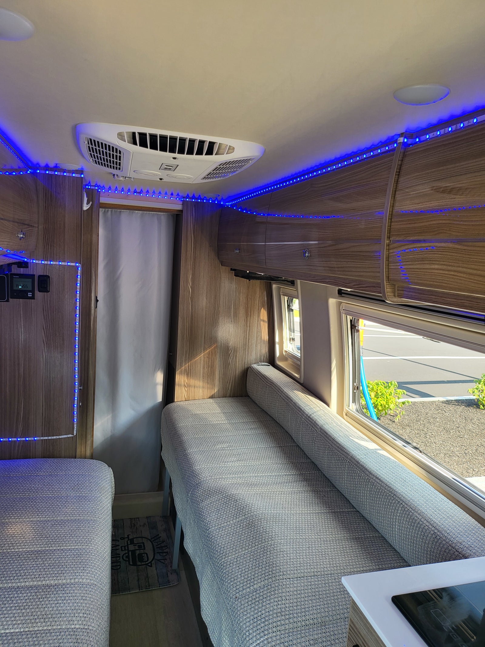 Interior of an **rv rental** showing a cozy living space with bright blue LED lights, a ceiling AC unit, and wood cabinetry.