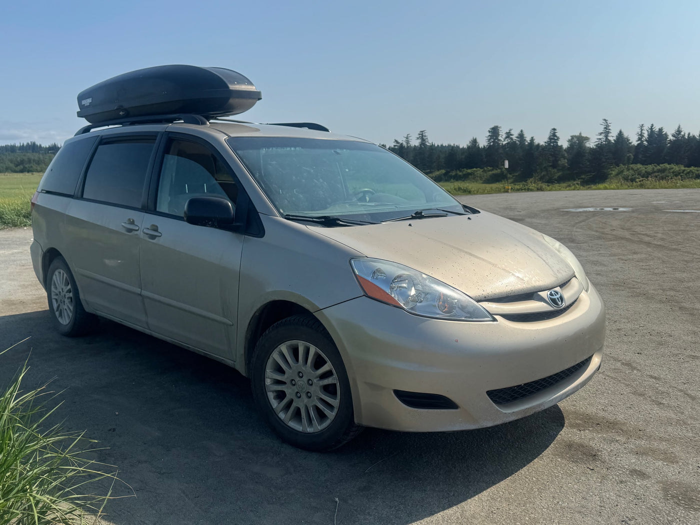 parked by the ocean. Roof rack has a large cargo box.|Minivan with a DIY bed platform for an RV rental adventure — photo 10