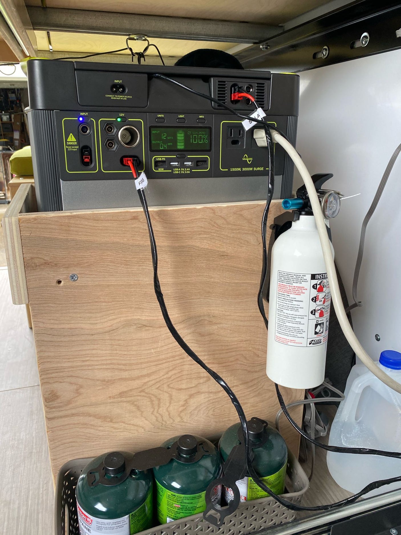 Inside an RV rental: Goal Zero portable power station, propane tanks, and fire extinguisher for off-grid power.