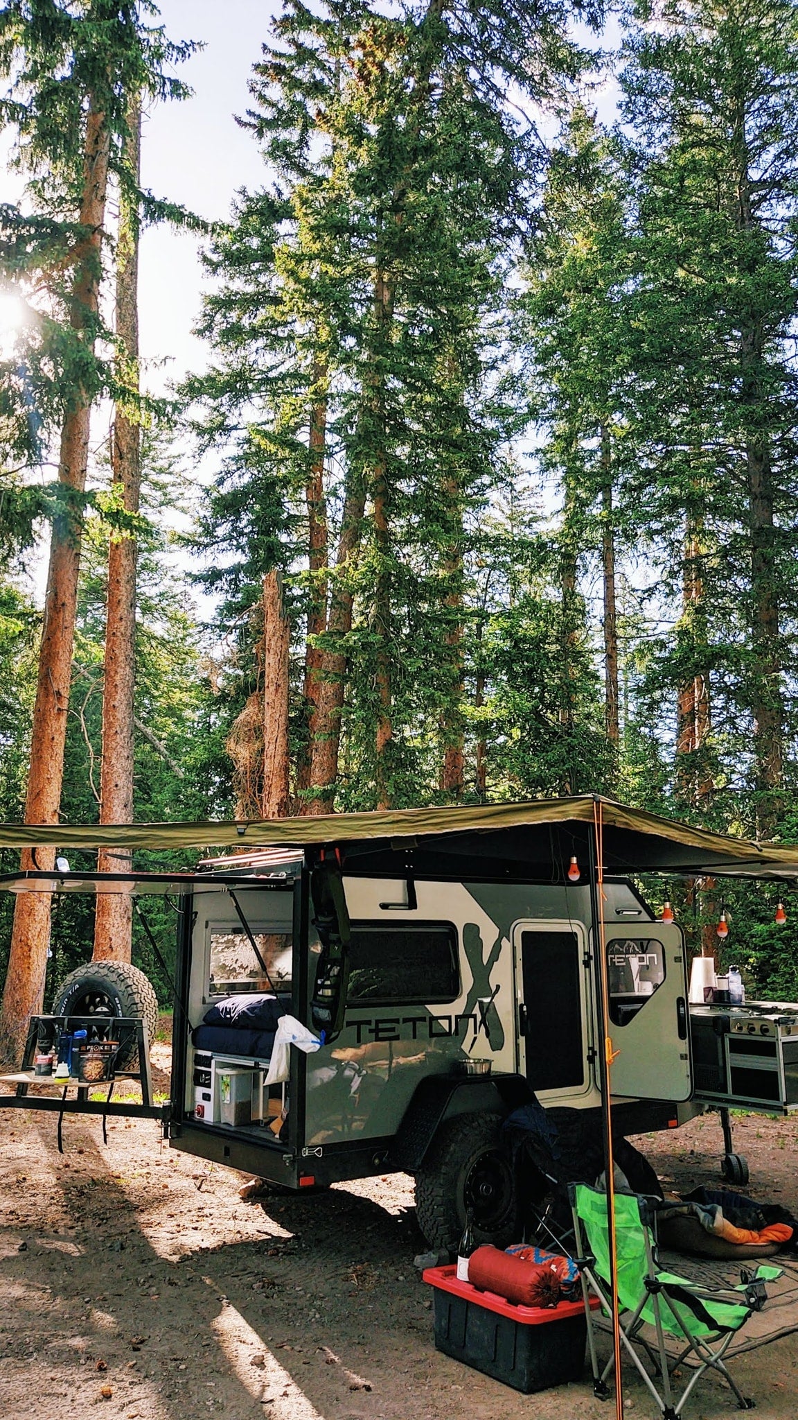 parked on gravel.|Adventure awaits! This off-grid teardrop **rv rental** in a serene forest setting offers the perfect escape for camping & outdoor fun.|An RV rental: TETONX adventure trailer and Jeep on a road in a scenic red rock canyon under blue sky.|Inside this RV rental: A cozy sleeping space with a bed