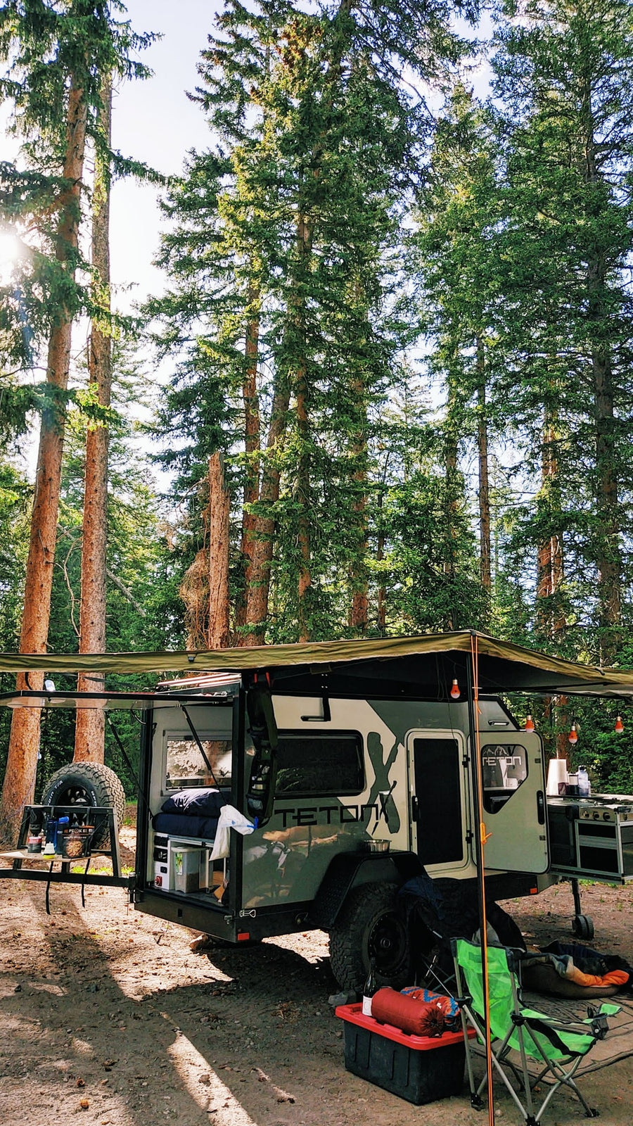 parked on gravel.|Adventure awaits! This off-grid teardrop **rv rental** in a serene forest setting offers the perfect escape for camping & outdoor fun.|An RV rental: TETONX adventure trailer and Jeep on a road in a scenic red rock canyon under blue sky.|Inside this RV rental: A cozy sleeping space with a bed